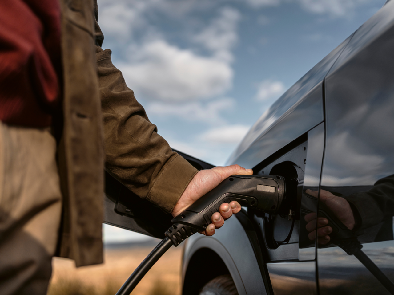 A person plugging in a charging socket into a Lexus